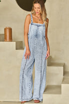 Light wash denim wide leg overalls from Thread Bar Boutique featuring frayed edges, reverse seam detailing, and relaxed fit for casual weekend outfits.