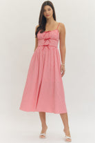Model wearing a sweetheart gingham maxi dress with adjustable straps, bow details, smocked back, and side pockets in a romantic gingham print, perfect for Valentine’s Day and spring occasions.
