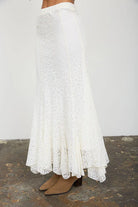 Women's flowy cream lace midi skirt from Thread Bar Boutique with soft lace detailing, a comfortable elastic waist, and feminine godet panels. Chic boutique clothing for special occasions and everyday elegance.