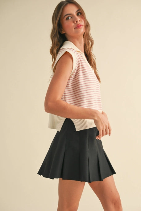 A model wearing a pink striped sleeveless knit vest with a V-neckline and ribbed hem