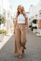 Blonde model in candid walking shot wearing khaki polka dot wide leg pants, fabric flowing in motion — Thread Bar Boutique