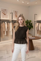 Women's semi-sheer peplum blouse with textured shirring, fitted silhouette, cap sleeves, and soft lightweight knit fabric.