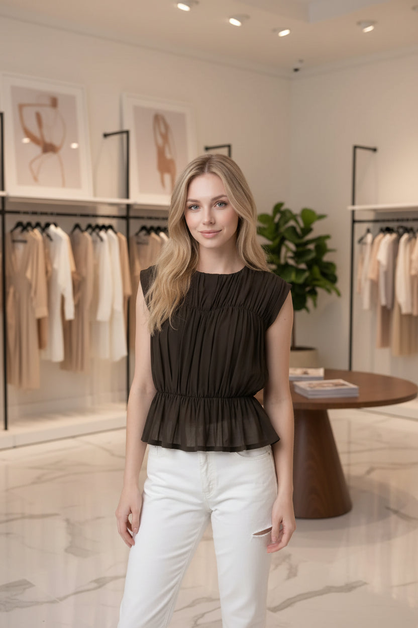 Women's semi-sheer peplum blouse with textured shirring, fitted silhouette, cap sleeves, and soft lightweight knit fabric.