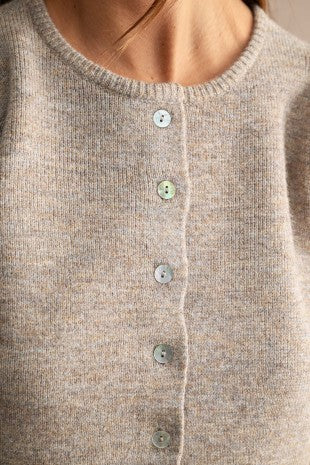 Detailed view of a soft women's knit sweater featuring textured fabric, subtle stretch, structured puff sleeves, crew neck, and button-down front for elevated casual style.