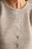 Detailed view of a soft women's knit sweater featuring textured fabric, subtle stretch, structured puff sleeves, crew neck, and button-down front for elevated casual style.