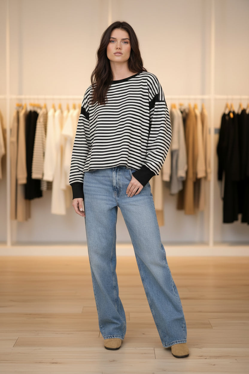 Side view of a striped knit top with a relaxed silhouette, drop shoulder design, contrast trim accents, and soft stretch fabric from Thread Bar Boutique.