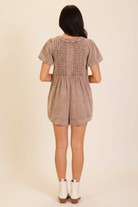  Vintage-inspired washed romper with short sleeves, relaxed fit, cuffed hem shorts, and feminine front tie detail from Thread Bar Boutique