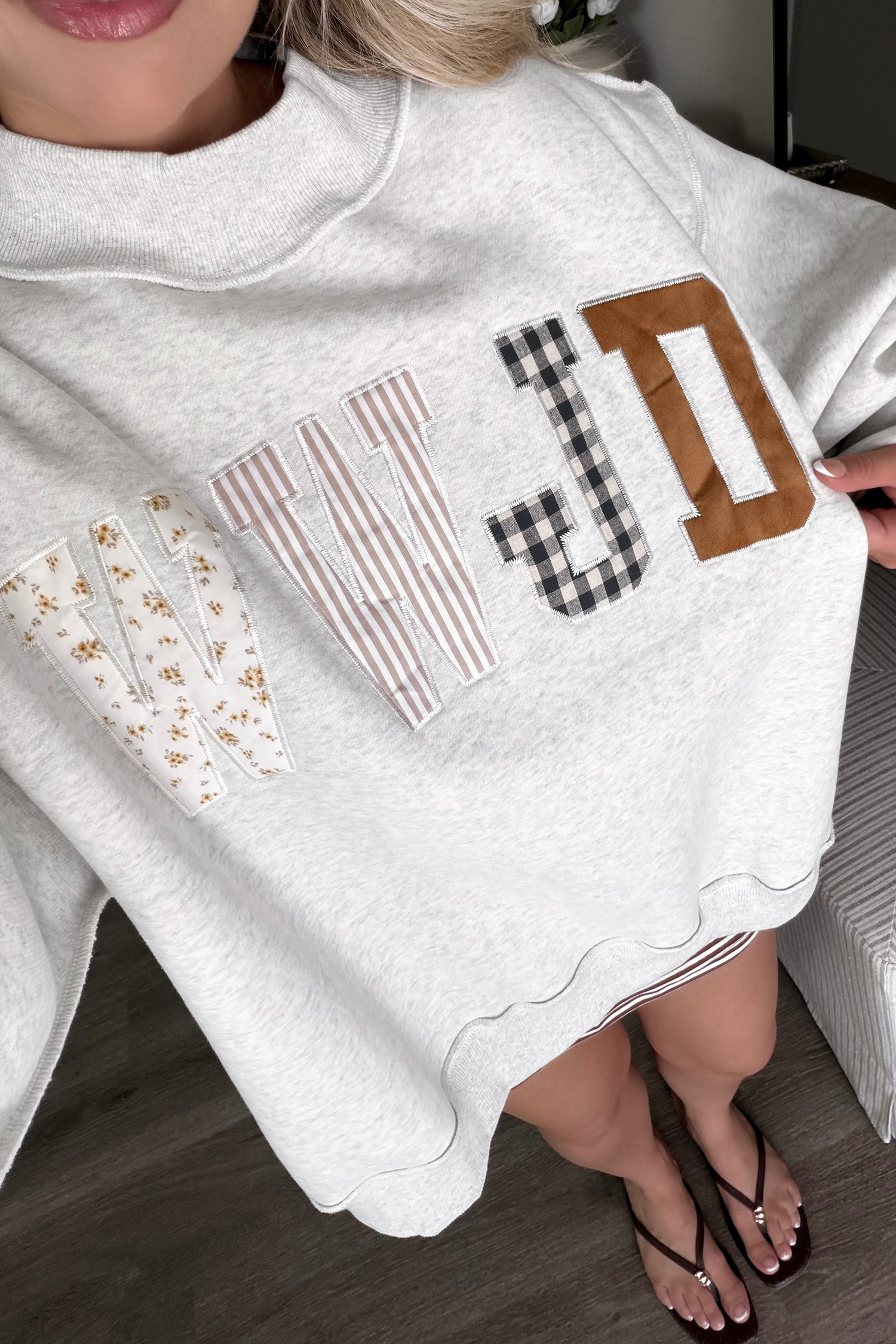 Close-up of women's WWJD Christian sweatshirt featuring bold embroidered lettering, floral, plaid, and striped fabric patches, and detailed stitched appliqué for a unique faith-inspired graphic design.