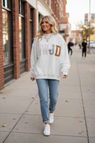 Detailed view of WWJD embroidered appliqué on a women's Christian sweatshirt, showcasing colorful floral, plaid, and striped fabric patches combined with decorative embroidery
