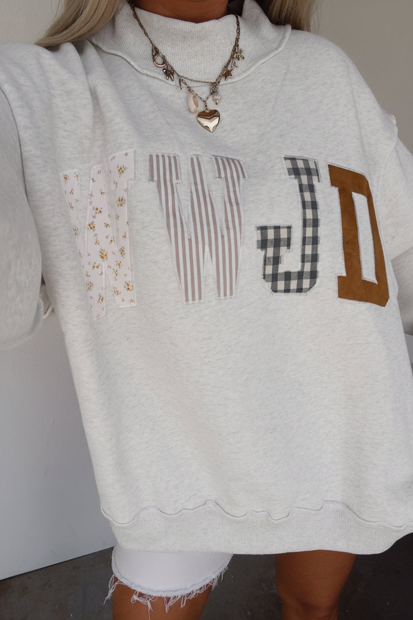 Women's WWJD embroidered patch sweatshirt with mixed floral, plaid, and striped fabric appliqué details, mock neck, long sleeves, and relaxed fit — a cozy Christian faith sweatshirt for everyday wear.
