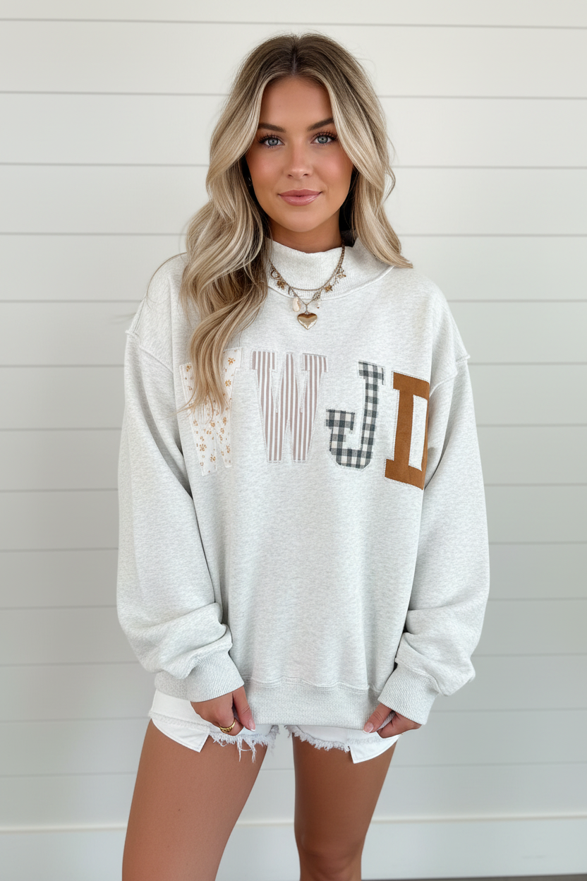 Women's heather gray oversized WWJD mock neck sweatshirt with mixed patchwork appliqué lettering in floral, stripe, and buffalo plaid — full body front view styled with micro denim shorts