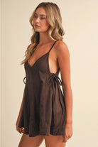 Women’s chocolate brown flare romper styled for a summer outfit with adjustable tie waist, V-neckline, and strappy silhouette