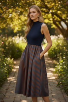 Women's contrast stripe midi dress featuring a solid mock neck bodice, sleeveless silhouette, bold vertical striped skirt, side pockets, and lightweight fully lined construction.