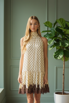 Women’s polka dot midi dress with cream base, brown dot print, relaxed drop waist fit, feminine peplum hem, and midi length
