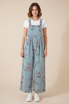 Floral denim wide leg overalls from Thread Bar Boutique featuring pink and sage print, pleated waist detail, and vintage-inspired silhouette.