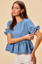 Blue denim bow top with peplum hem styled for everyday wear at Thread Bar Boutique