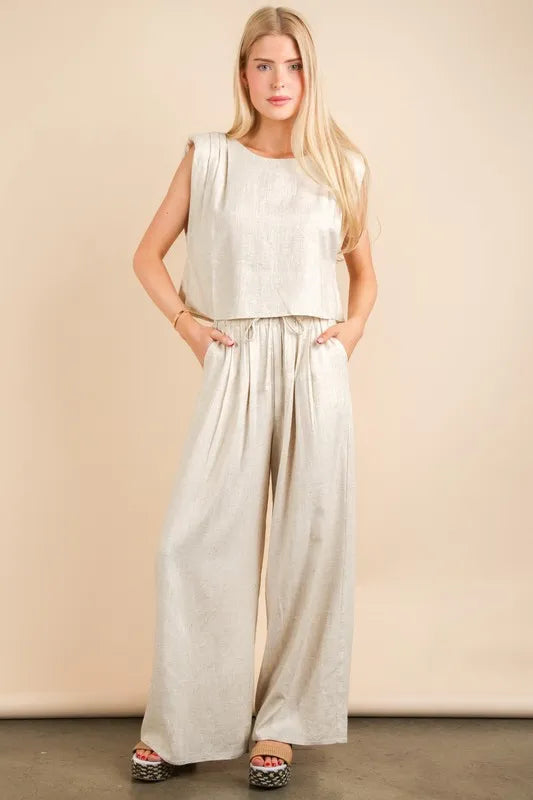  woman wearing a beige woven two-piece set with wide-leg pants and a sleeveless cropped top, styled for a chic minimalist look