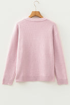 Pink sweater on a wooden hanger against a white background