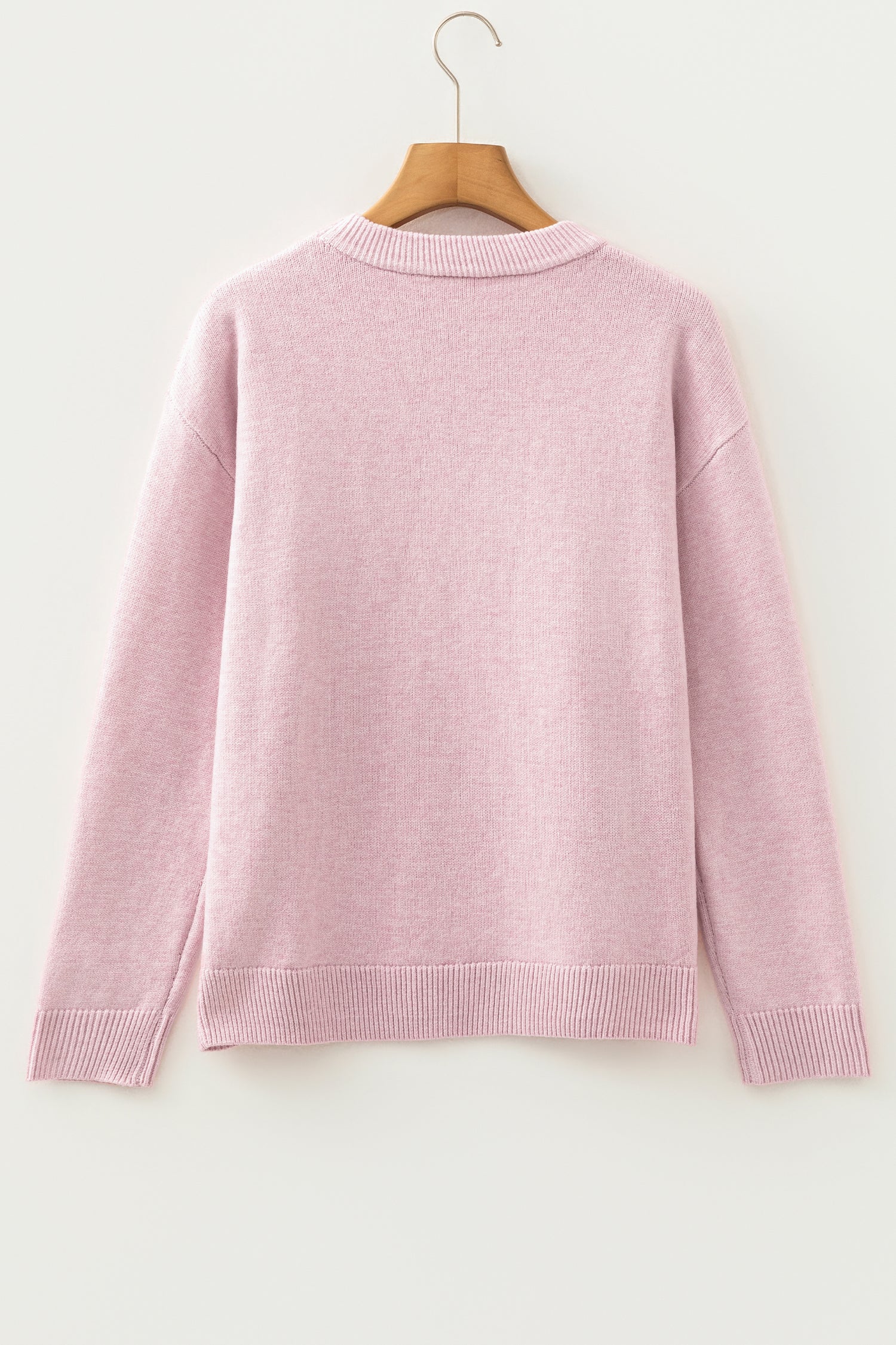Pink sweater on a wooden hanger against a white background