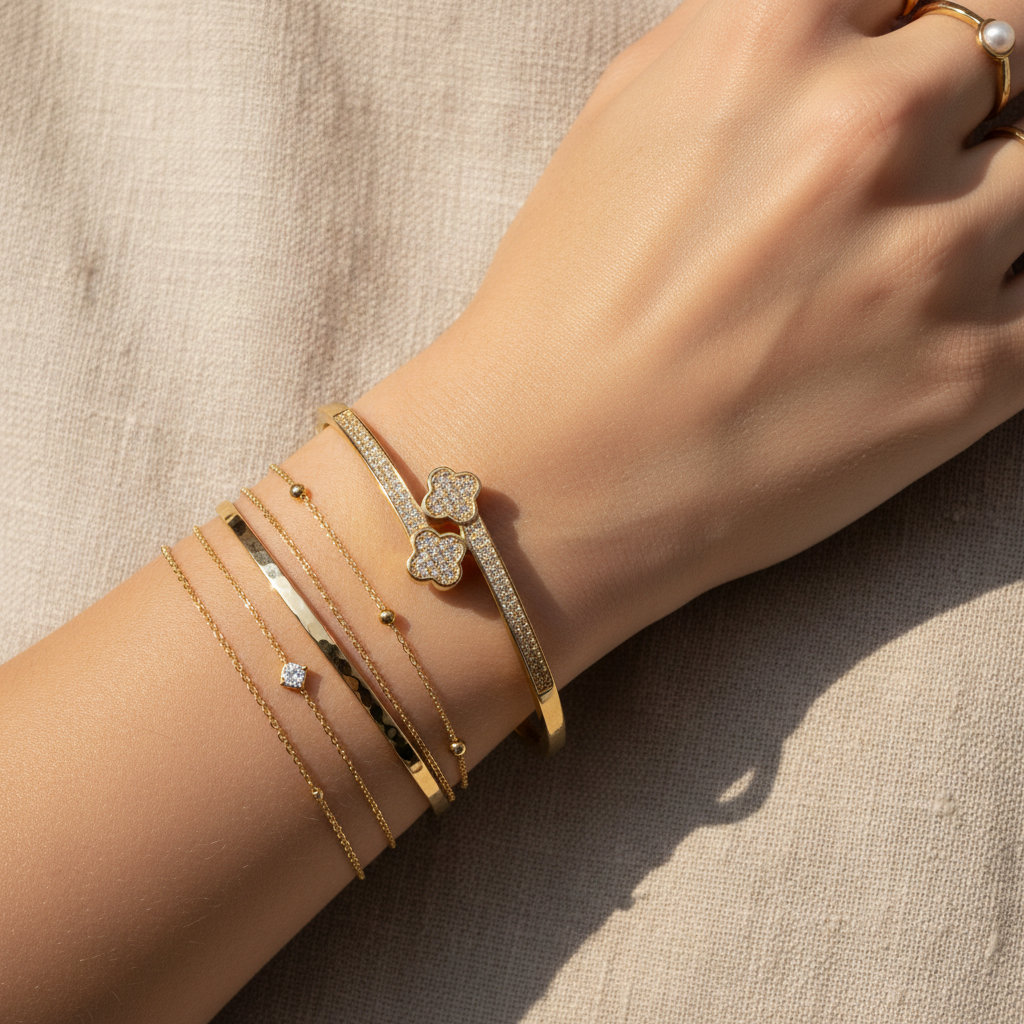 Double Clover Cubic Zirconia Bangle styled on wrist with delicate gold jewelry