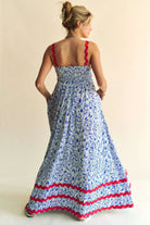 Woman wearing a patriotic-themed maxi dress with a blue and white heart pattern, red scalloped trim, and smocked bodice