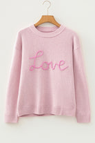 Women’s pink LOVE graphic knit sweater with relaxed fit, round neckline, and dropped shoulders