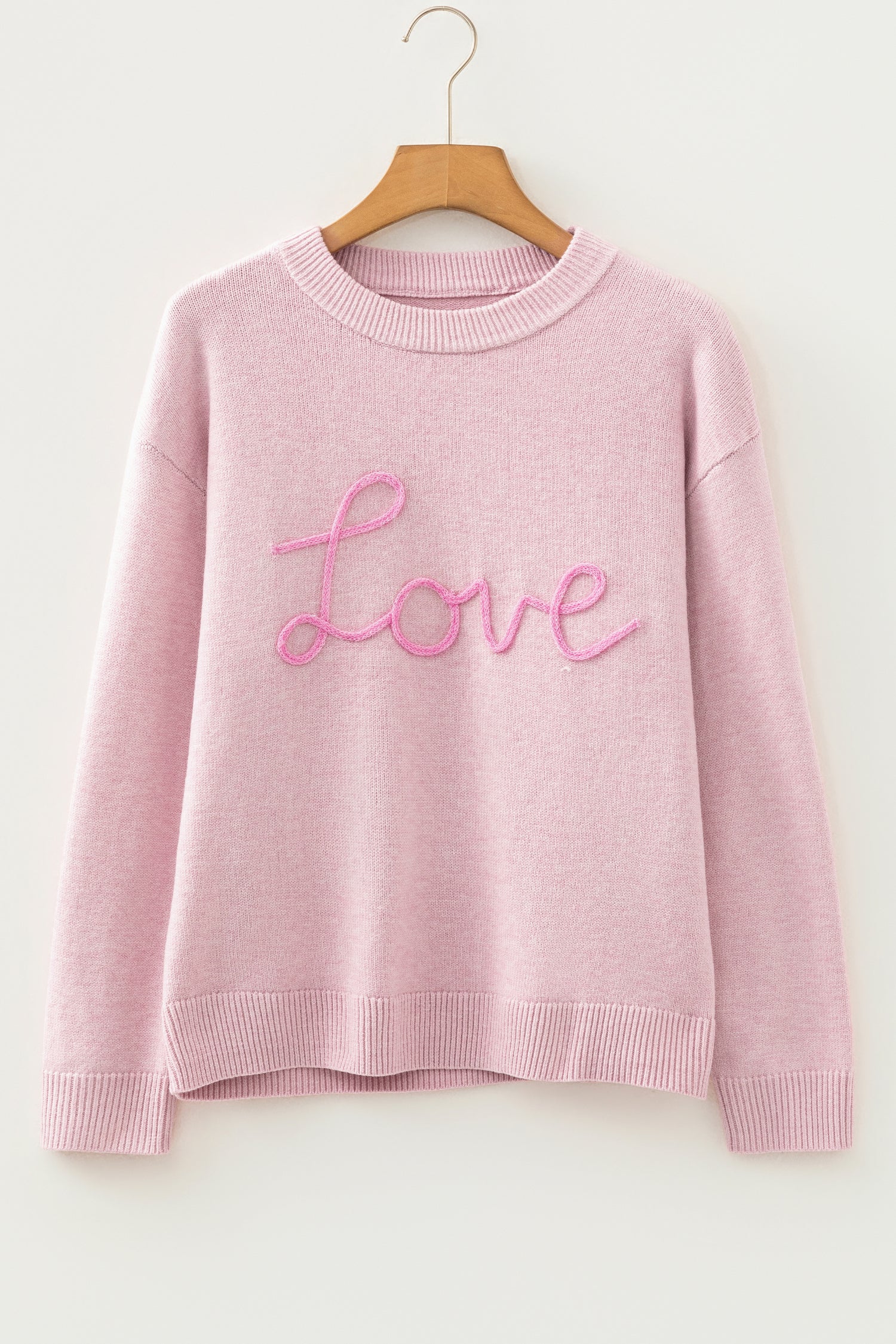 Women’s pink LOVE graphic knit sweater with relaxed fit, round neckline, and dropped shoulders