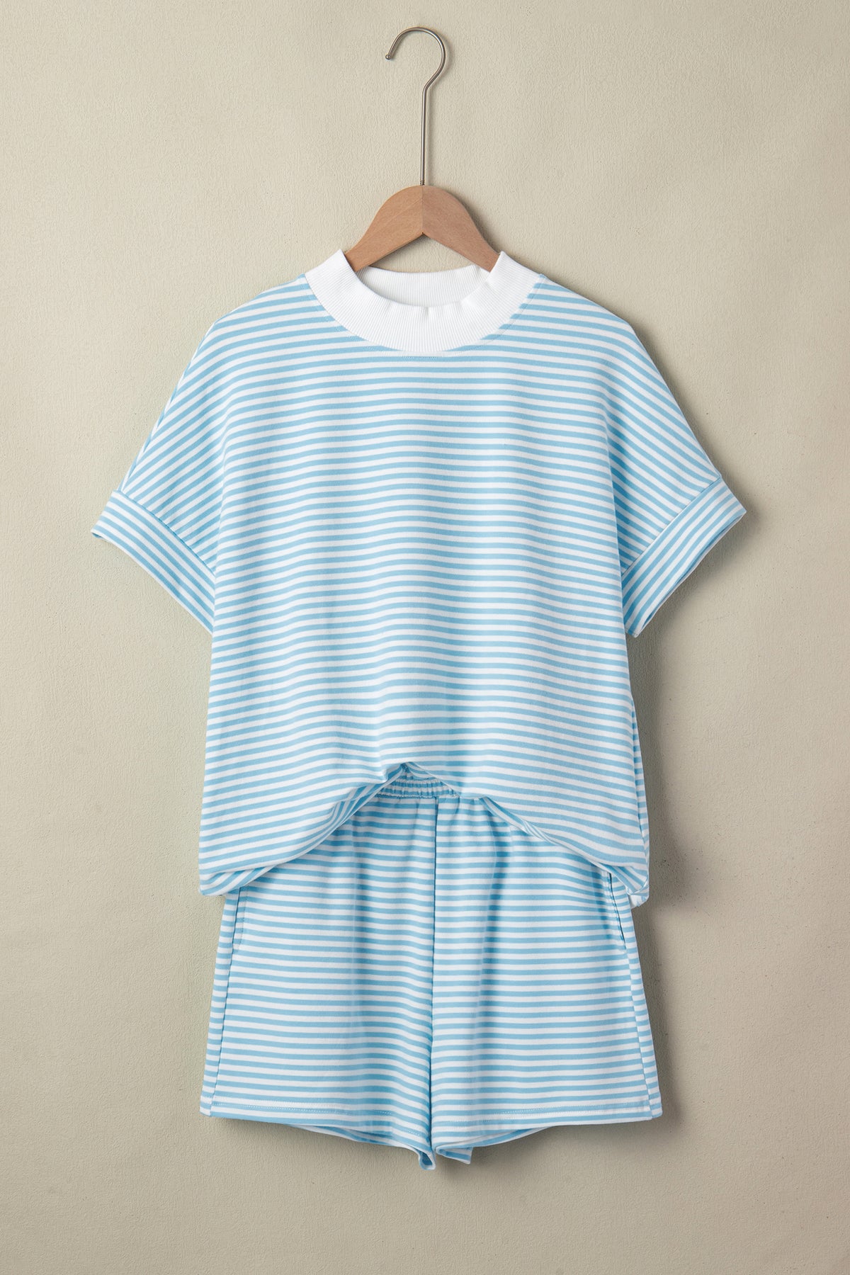 Blue and white striped outfit on a hanger against a beige background