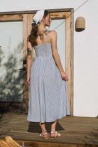 Rear view of a striped midi dress showcasing a functional smocked back dress panel for an adjustable fit. The taupe stripes remain continuous from the shoulder straps down to the hem of the A-line summer dress