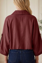Back detail of taupe utility jacket showing folded collar, woven fabric, button-tab sleeves and gathered elastic hem