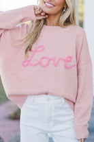 Women’s pink LOVE graphic knit sweater with relaxed fit, round neckline, and dropped shoulders