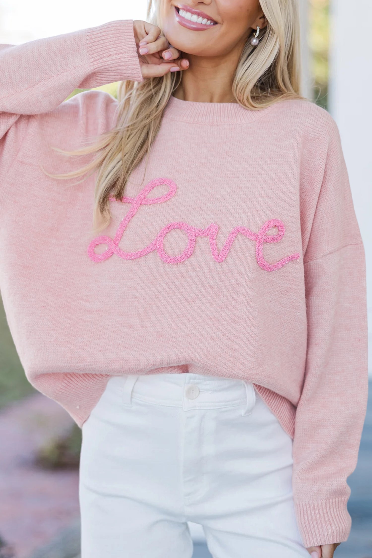 Women’s pink LOVE graphic knit sweater with relaxed fit, round neckline, and dropped shoulders