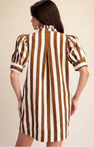 A woman shown from the back wearing a brown and white vertically striped dress with puff sleeves and a ruffled high neck, against a plain beige studio background.