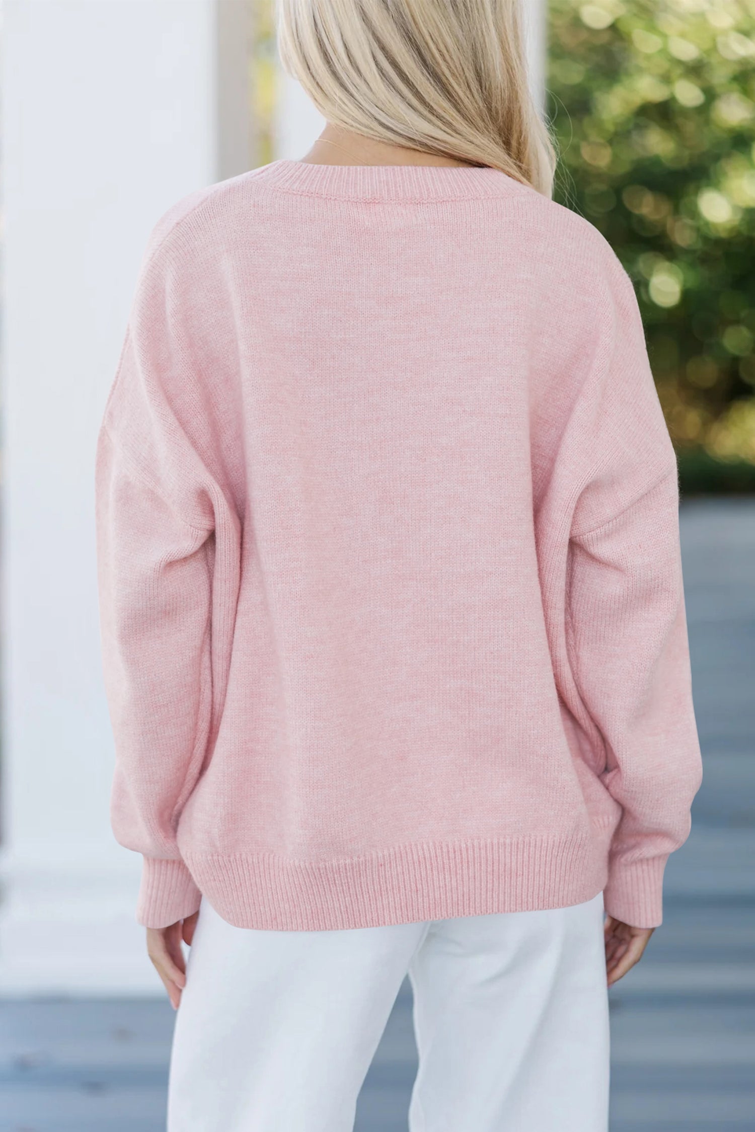 Women’s pink LOVE graphic knit sweater with relaxed fit, round neckline, and dropped shoulders