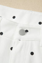 White fabric with black polka dots and a metal button 