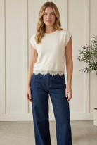 Entro cream cap sleeve sweater top with a round neckline and delicate lace trim hem, styled with dark wide-leg jeans.