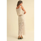 A model wearing a cream-colored crochet crop top and matching maxi skirt with a tie waist and built-in slip, styled with platform sandals against a neutral backdrop.