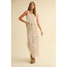 A model wearing a cream-colored crochet crop top and matching maxi skirt with a tie waist and built-in slip, styled with platform sandals against a neutral backdrop.