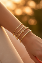 CZ Triple Heart Stainless Steel Bangle stacked with gold bangles in golden hour light