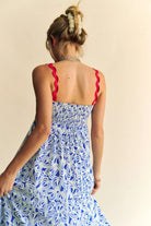 Woman wearing a patriotic-themed maxi dress with a blue and white heart pattern, red scalloped trim, and smocked bodice