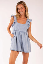  A stylish denim romper featuring delicate ruffle sleeves, a scoop neckline, and a tie-back detail. Designed with a relaxed fit in lightweight denim, this romper includes side pockets for a blend of practicality and effortless summer style. Perfect for casual outings and warm-weather adventures.