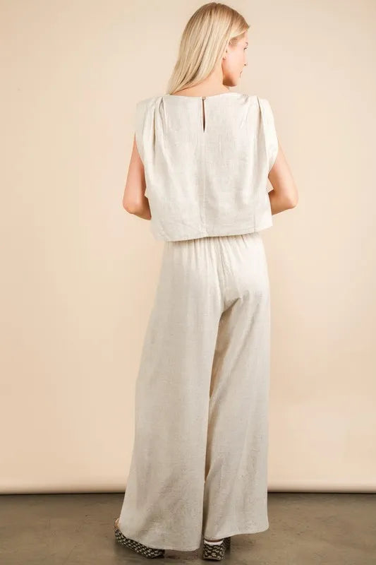  woman wearing a beige woven two-piece set with wide-leg pants and a sleeveless cropped top, styled for a chic minimalist look