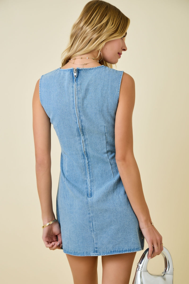 Woman wearing light blue denim sleeveless mini dress with diagonal bow tie details and exposed seam accents  zipper back