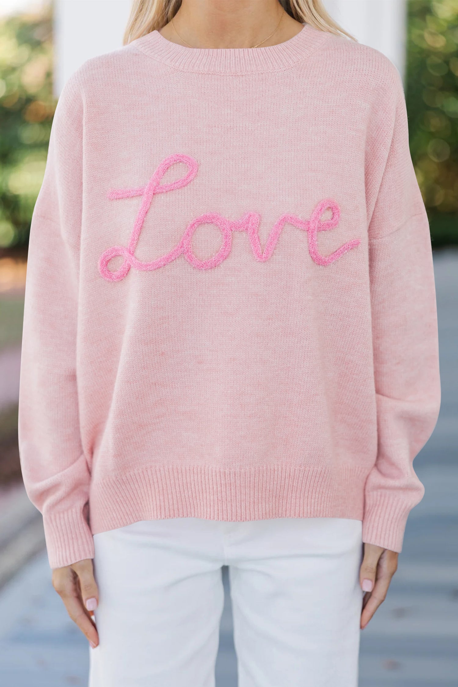 Women’s pink LOVE graphic knit sweater with relaxed fit, round neckline, and dropped shoulders