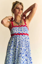 Woman wearing a patriotic-themed maxi dress with a blue and white heart pattern, red scalloped trim, and smocked bodice