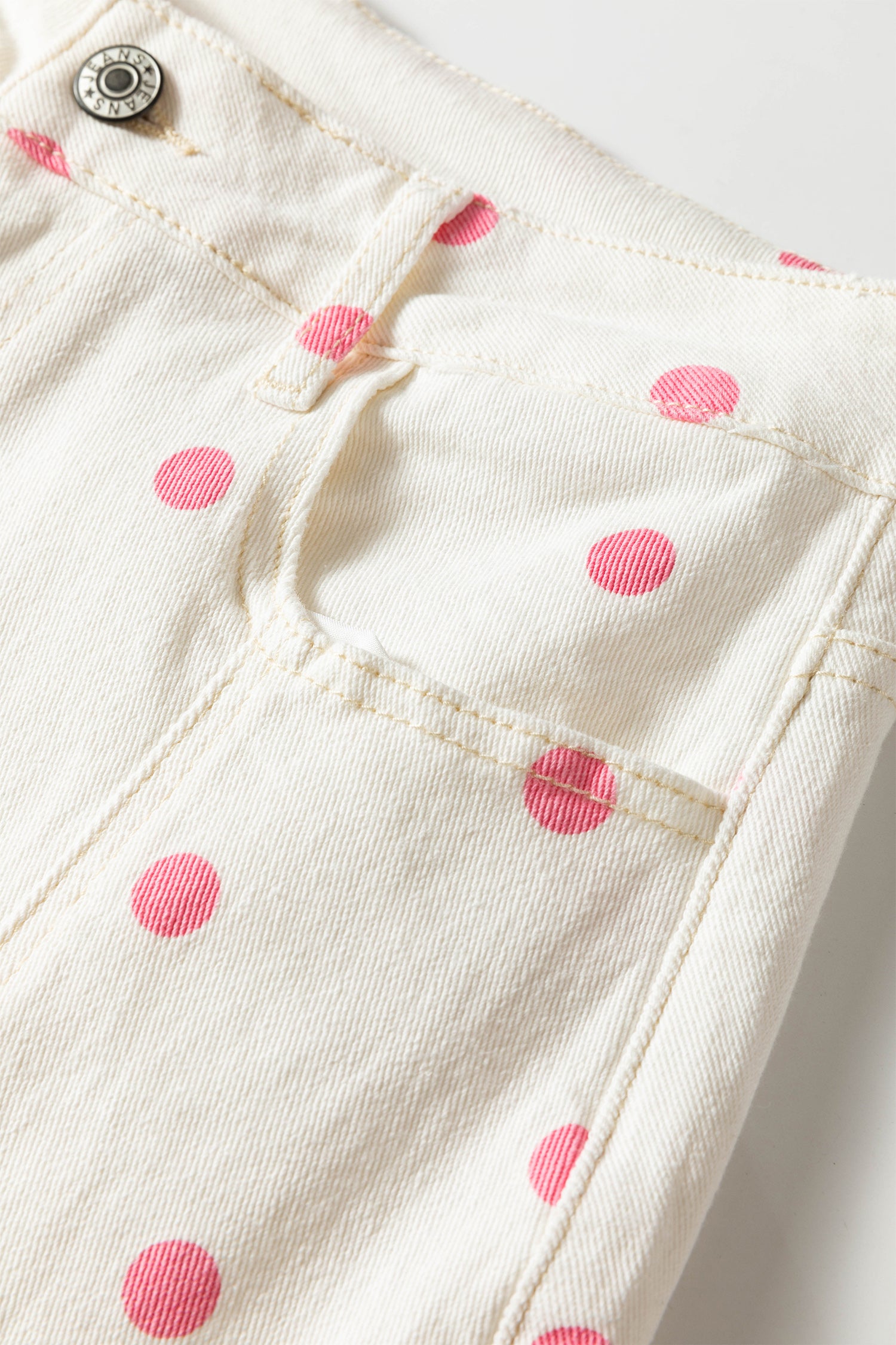 Close-up of white fabric with pink polka dots on a white background