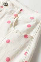 Close-up of white fabric with pink polka dots on a white background