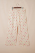 Polka dot pants on a hanger against a beige background