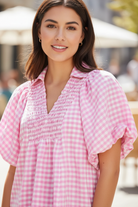 Close-up of Umgee pink gingham smocked yoke blouse — split V-neck collar and puff sleeve detail on brunette model