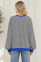 Back view of women's black and white striped sweatshirt showing oversized fit, long sleeves and blue ribbed hem.